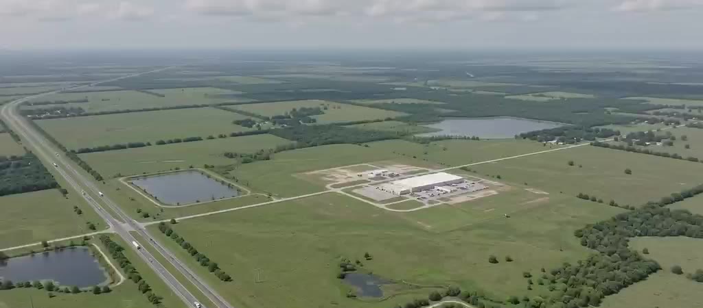 Aerial view of a Gulf Coast project site along a regional highway, showing the built facility footprint and stormwater ponds